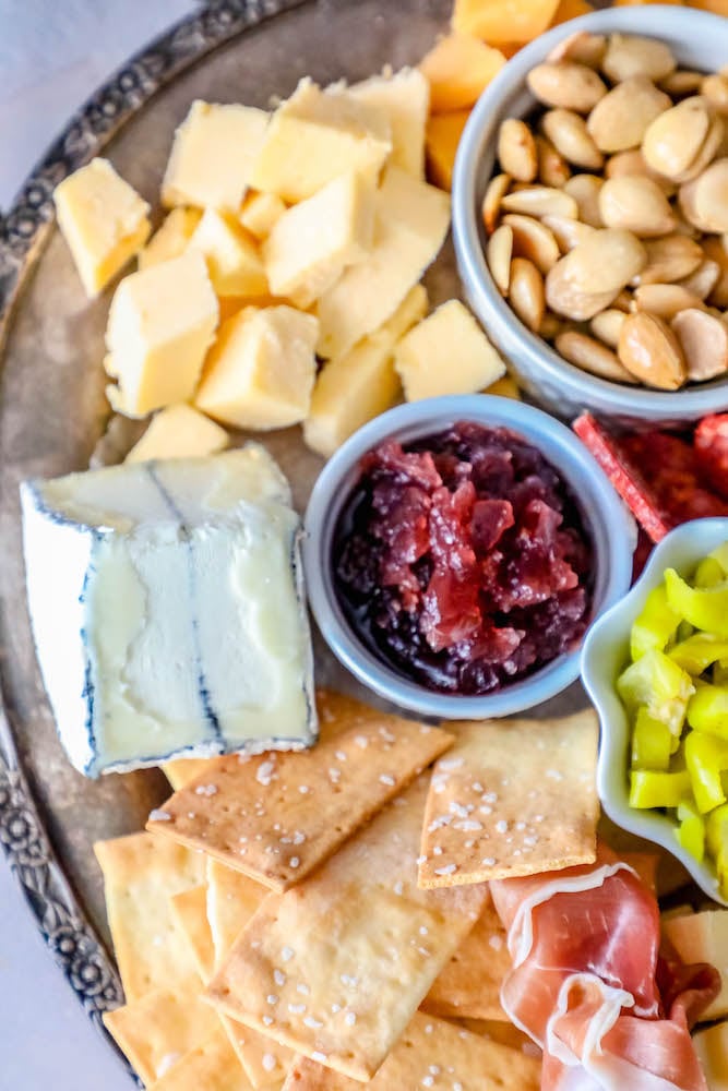 cheeses and jams and crackers with sliced meat on a tray