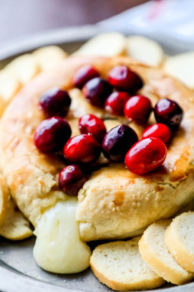 baked brie with cranberries on top oozing out of the puff pastry