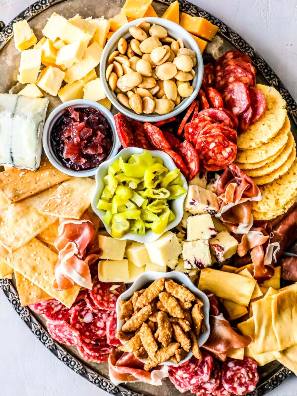 A platter with a variety of meats, cheeses and crackers.