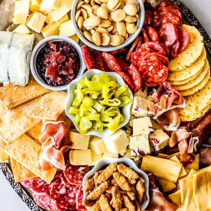 A platter with a variety of meats, cheeses and crackers.