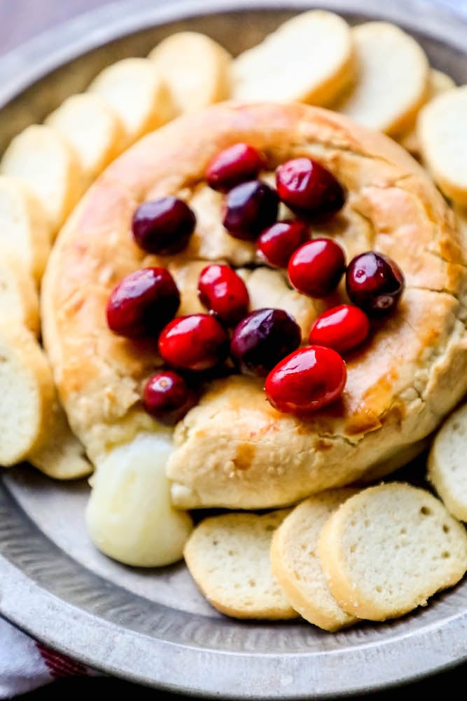 baked brie with cranberries on top oozing out of the puff pastry