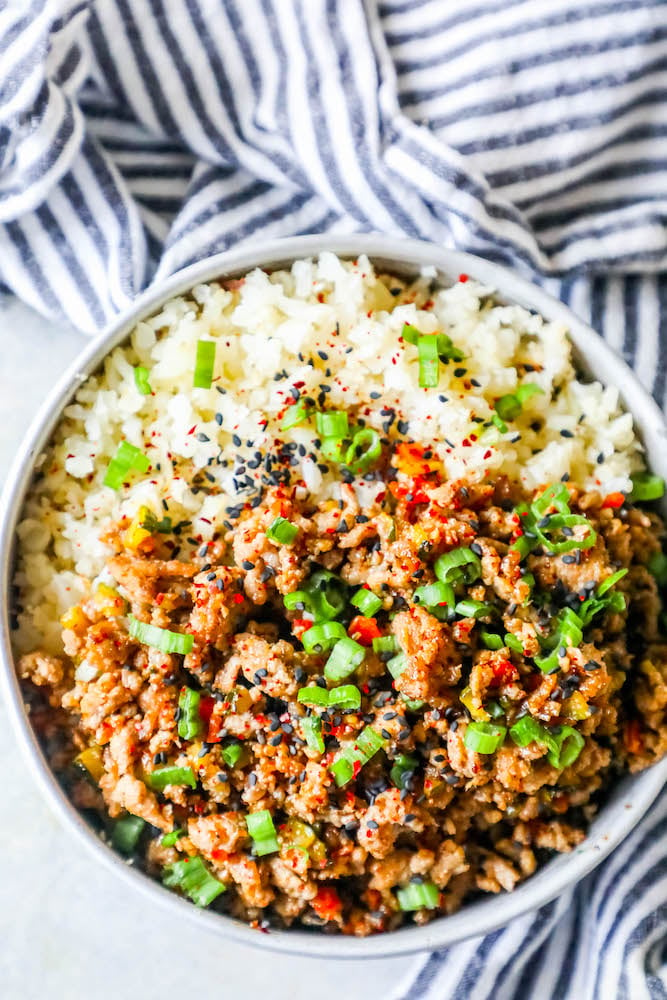 a bowl with rice, ground turkey, and green onions on it and sesame seeds