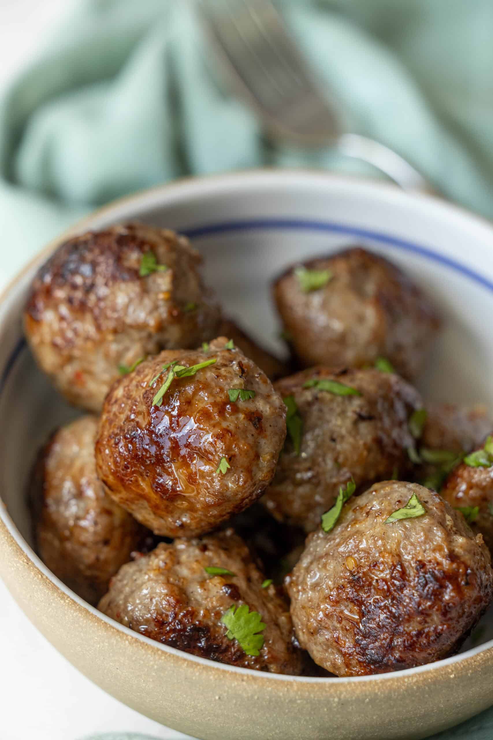 A bowl of Air Fried Meatballs garnished with fresh herbs.