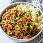 A bowl of spicy ground turkey served with Keto Teriyaki rice, garnished with green onions and sesame seeds.