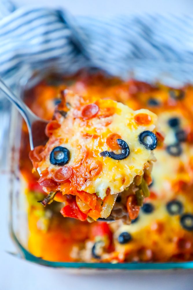 a scoop of casserole with vegetables and melted cheese and black olives on top