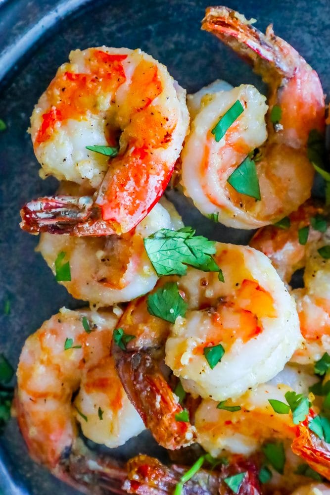 air fried shrimp on a plate covered in parmesan and garlic with chopped parsley