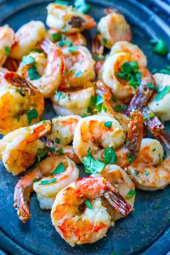 air fried shrimp on a plate covered in parmesan and garlic with chopped parsley