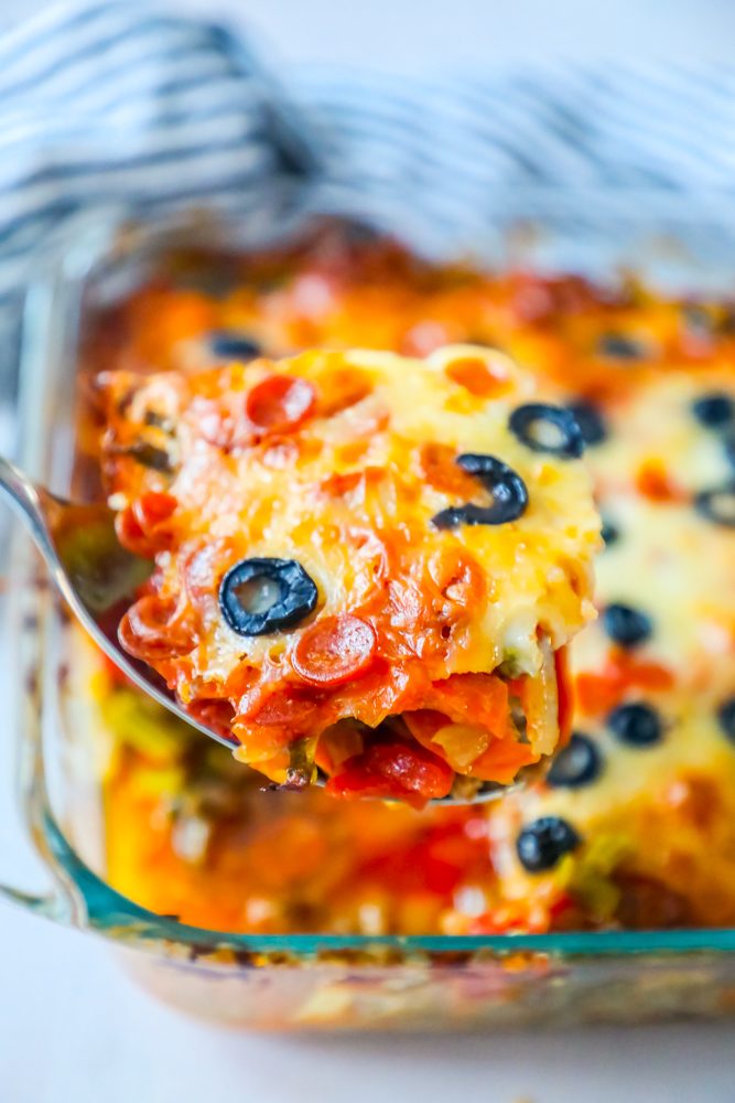 scoop of casserole with vegetables and melted cheese and black olives on top