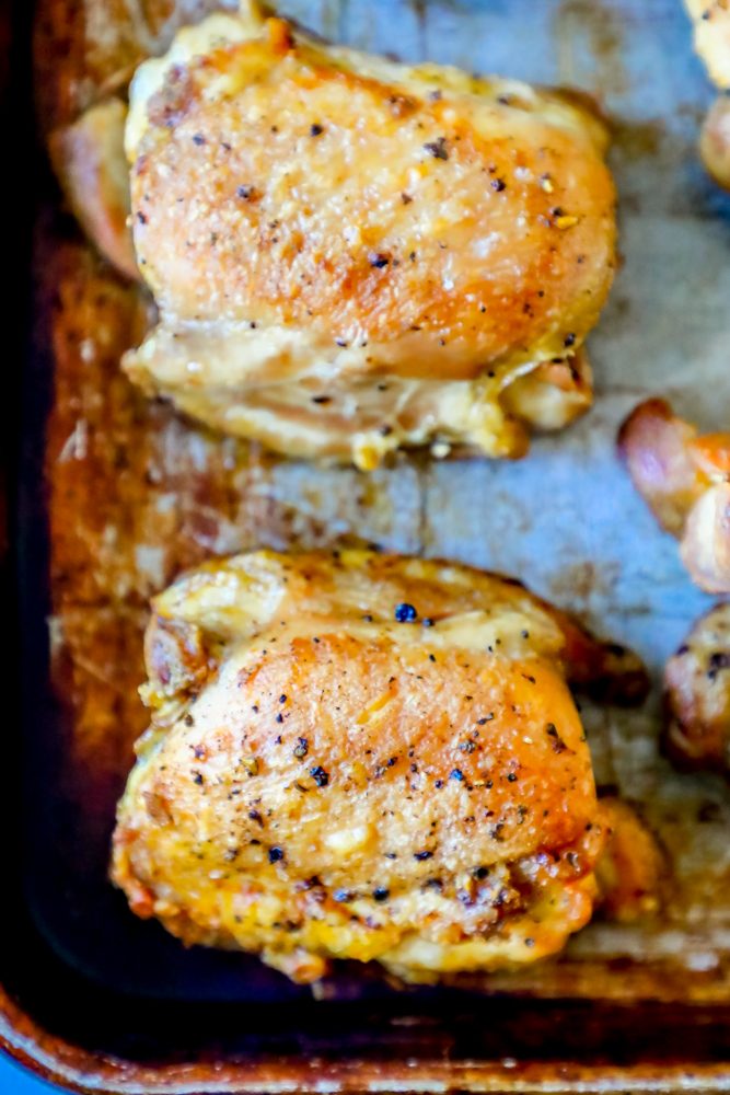 closeup picture of two chicken thighs on a baking sheet