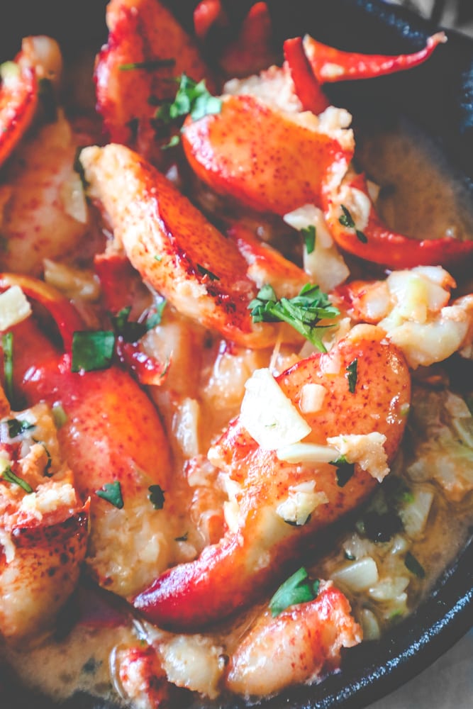 picture of lobsters in butter sauce and parsley up close