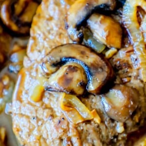 A close up of mushrooms and onions in a skillet, featured in a keto easy cube steak recipe.