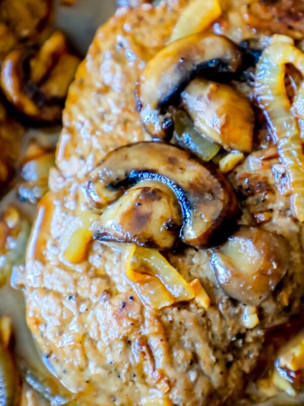 A close up of mushrooms and onions in a skillet, featured in a keto easy cube steak recipe.