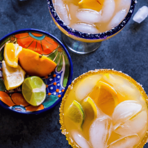 Two glasses of 4 Citrus Margaritas with limes and oranges.