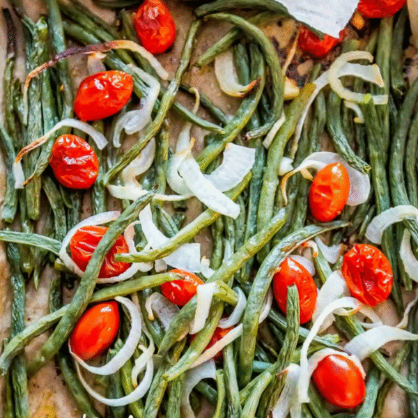 Roasted Green Bean Salad featuring cherry tomatoes and sliced onions, all perfectly arranged on a baking sheet.
