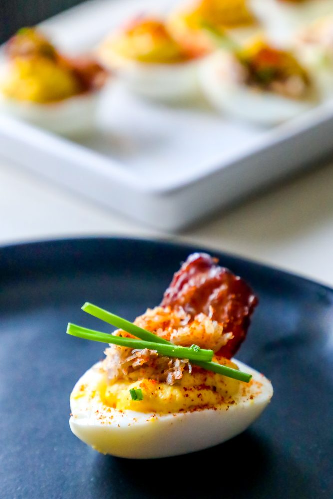 deviled egg with chives, crab, and bacon on it