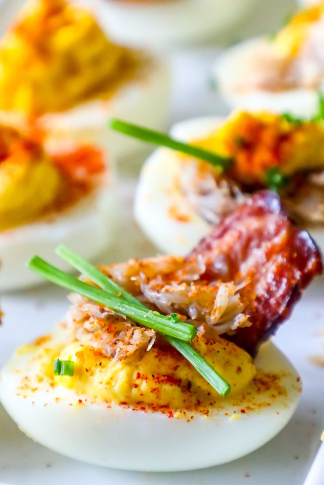 deviled egg with chives, crab, and bacon on it