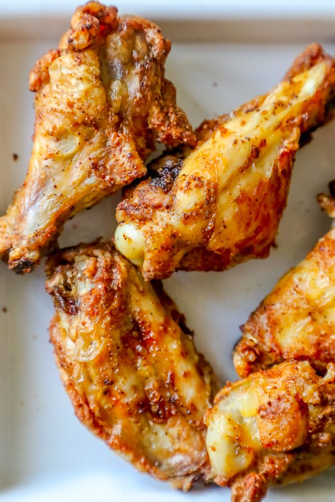 baked chicken wings covered in a spicy dry rub on a white plate