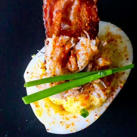 A deviled egg topped with bacon.