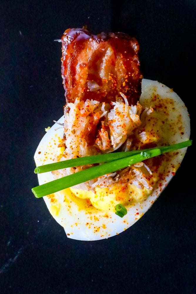 deviled egg with chives, crab, and bacon on it