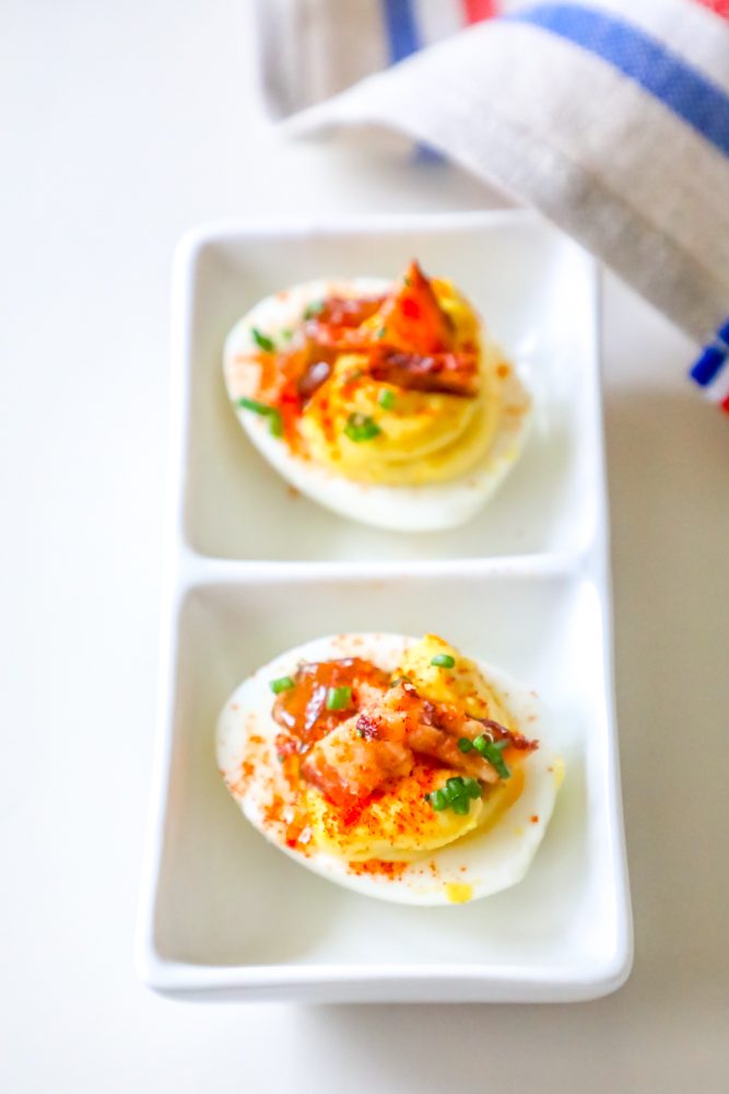hardboiled egg with creamy interior, bacon, chives, paprika, and jam
