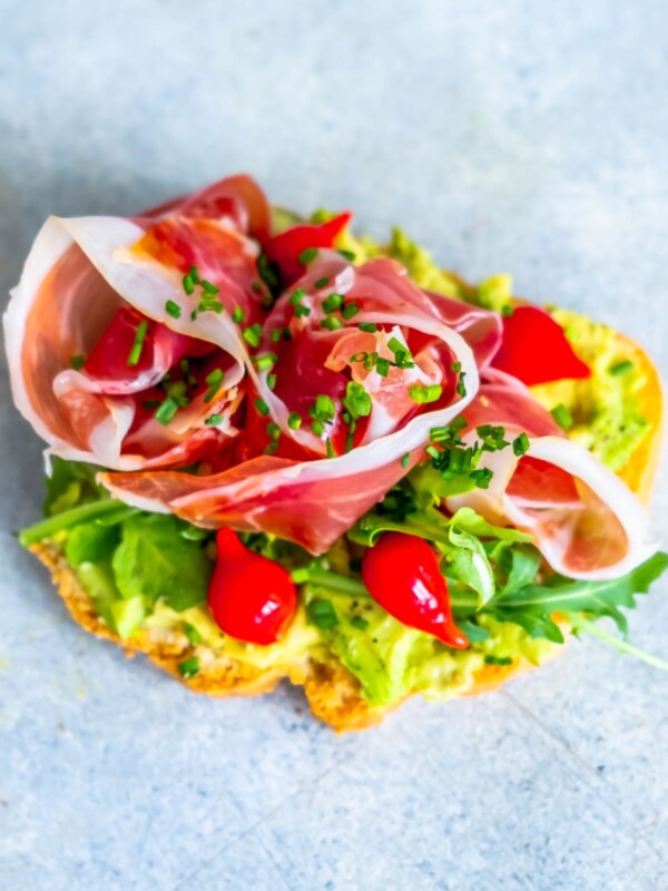 A low carb toast with ham and tomatoes on it.