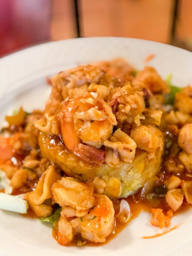 mofongo on a plate with shrimp and sauce over it 