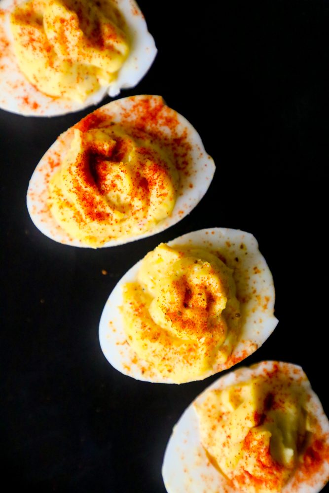 four deviled eggs with paprika sprinkled on top on a table