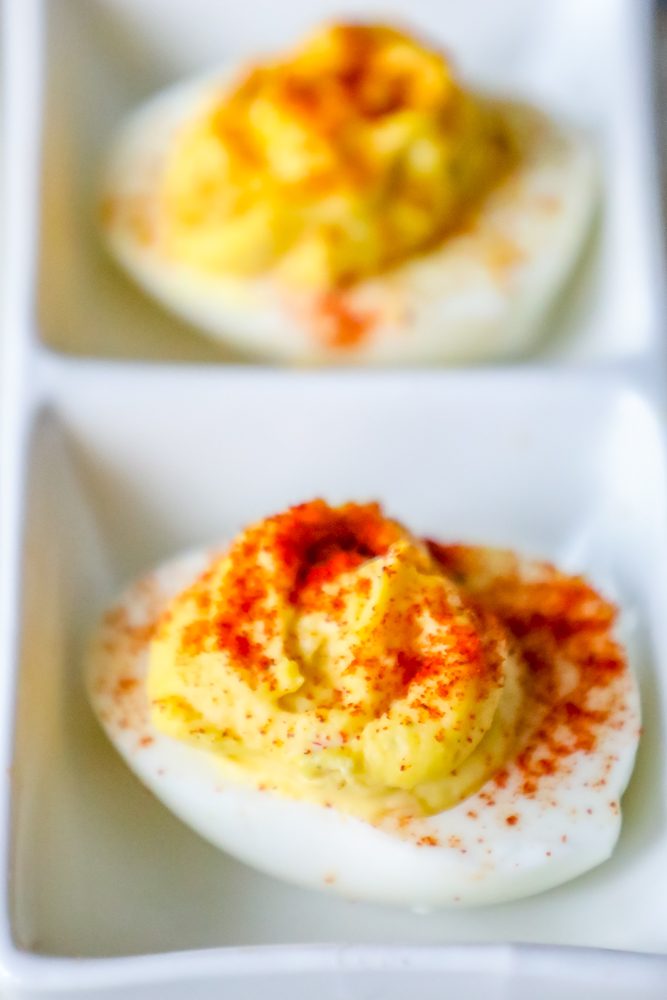 two deviled eggs with paprika sprinkled on top on a table