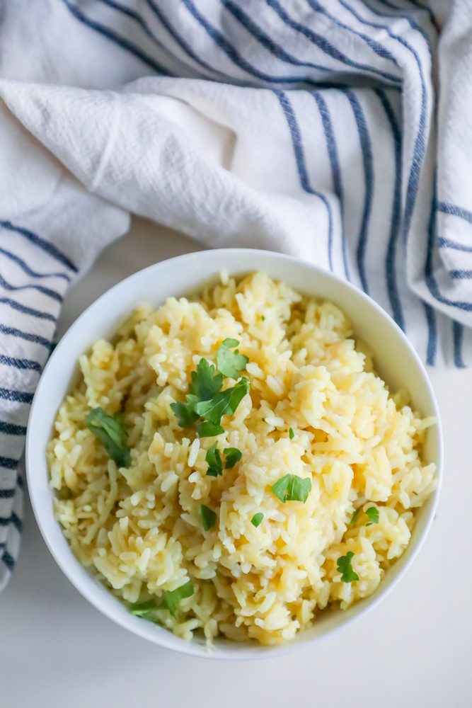 rice pilaf with parsley on it in a white bowl with towel around it