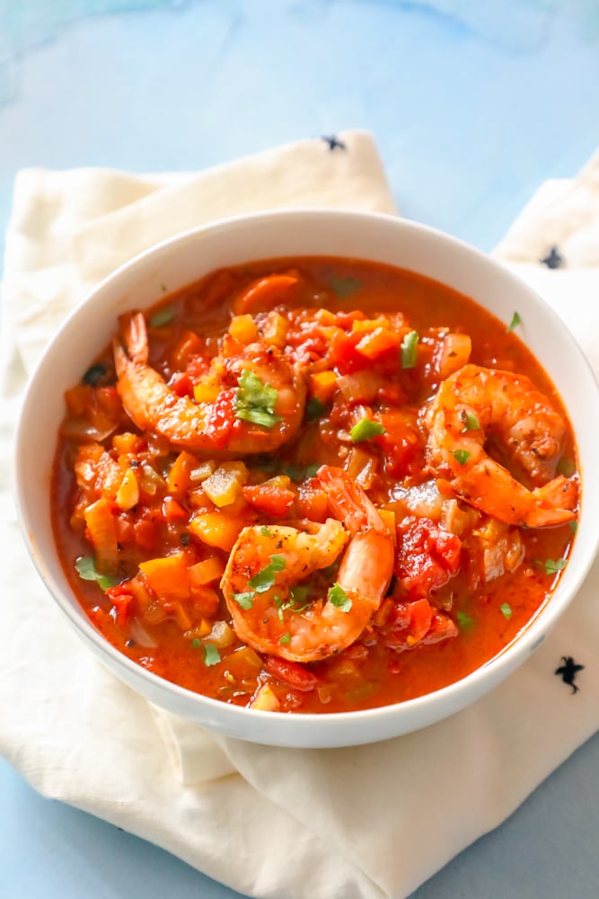 Shrimp Creole stew in a white bowl on a blue background.