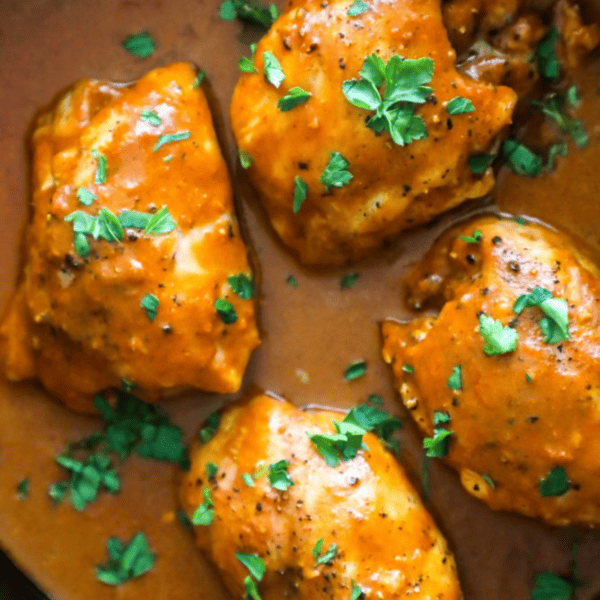 Keto Butter Chicken breasts in a skillet with sauce and parsley.