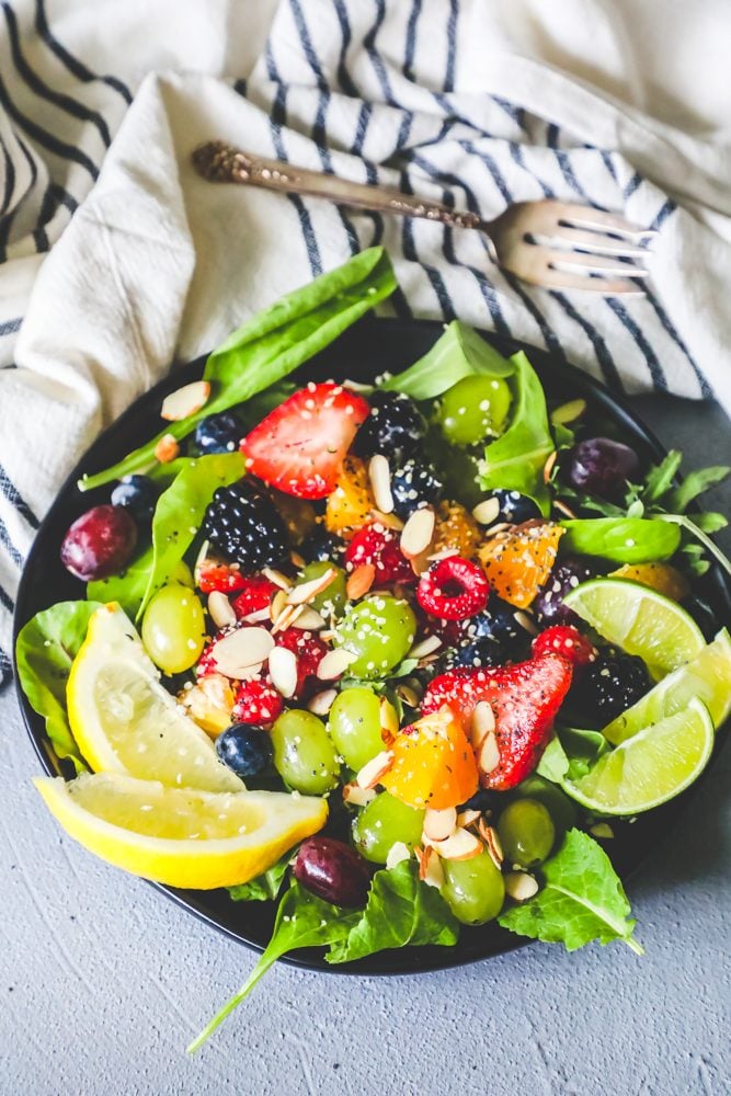  fruit salad with grapes, oranges, lemon, almonds, poppyseeds, strawberries, and lettuce in a bowl 