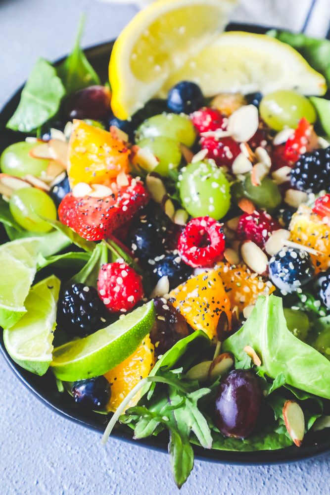 picture of fruit salad with grapes, oranges, lemon, almonds, poppyseeds, strawberries, and lettuce in a bowl 