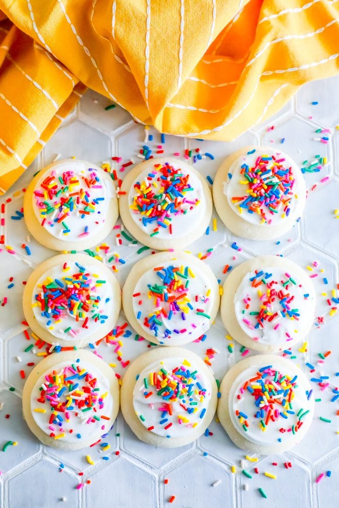 picture of iced sprinkled cookies oon a yellow tea towel 