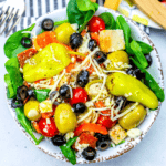 A Low Carb Grilled Chicken Antipasto Salad with olives, tomatoes, and spinach.