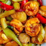 A close-up of shrimp stir fry featuring shrimp, sliced water chestnuts, bell peppers, celery, and peanuts in a glossy sauce. This easy Kung Pao shrimp recipe delivers a burst of flavors reminiscent of keto Chinese food delights.