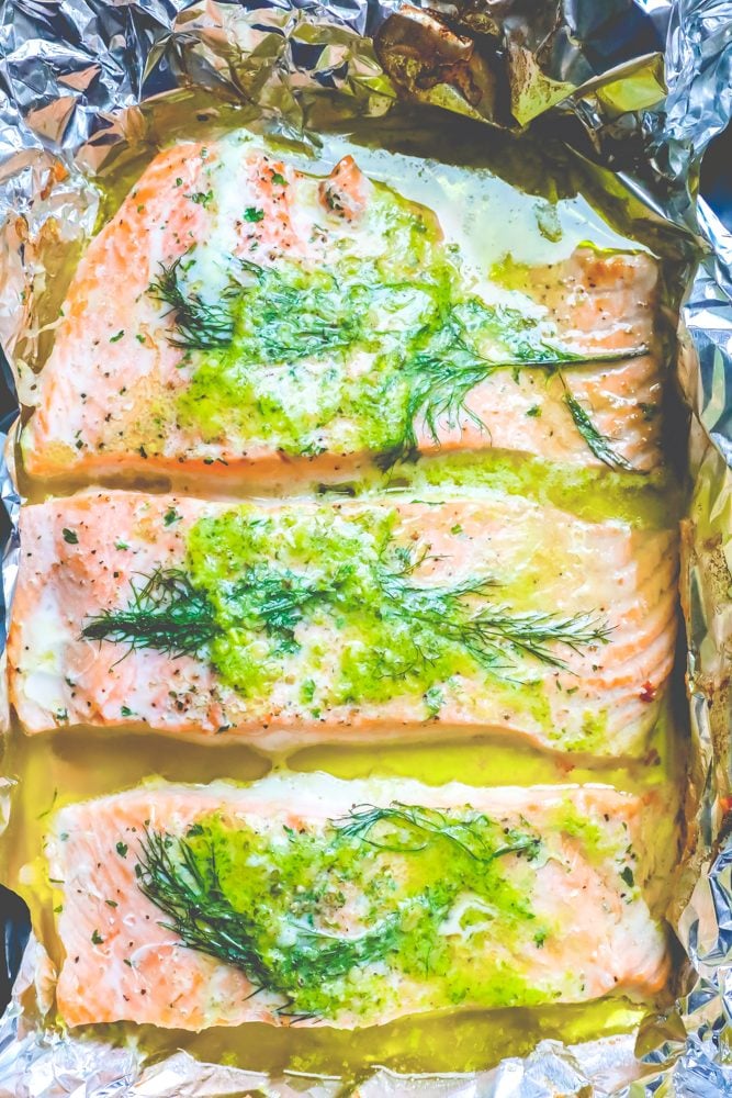 salmon on a tray with butter, pesto, and dill on it