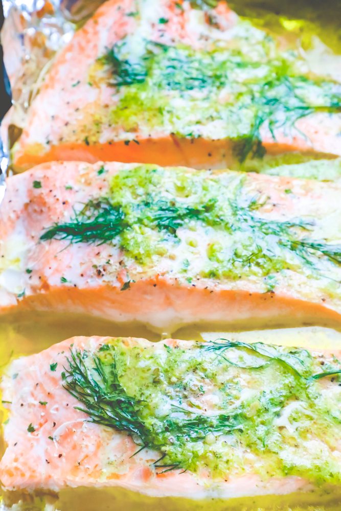 salmon on a tray with butter, pesto, and dill on it