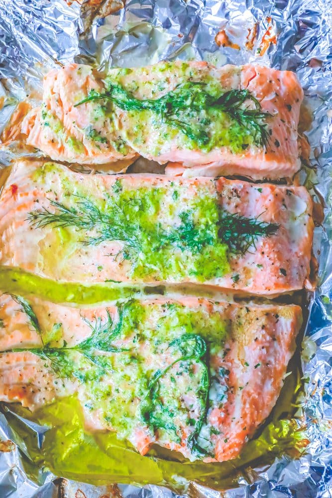 salmon on a tray with butter, pesto, and dill on it