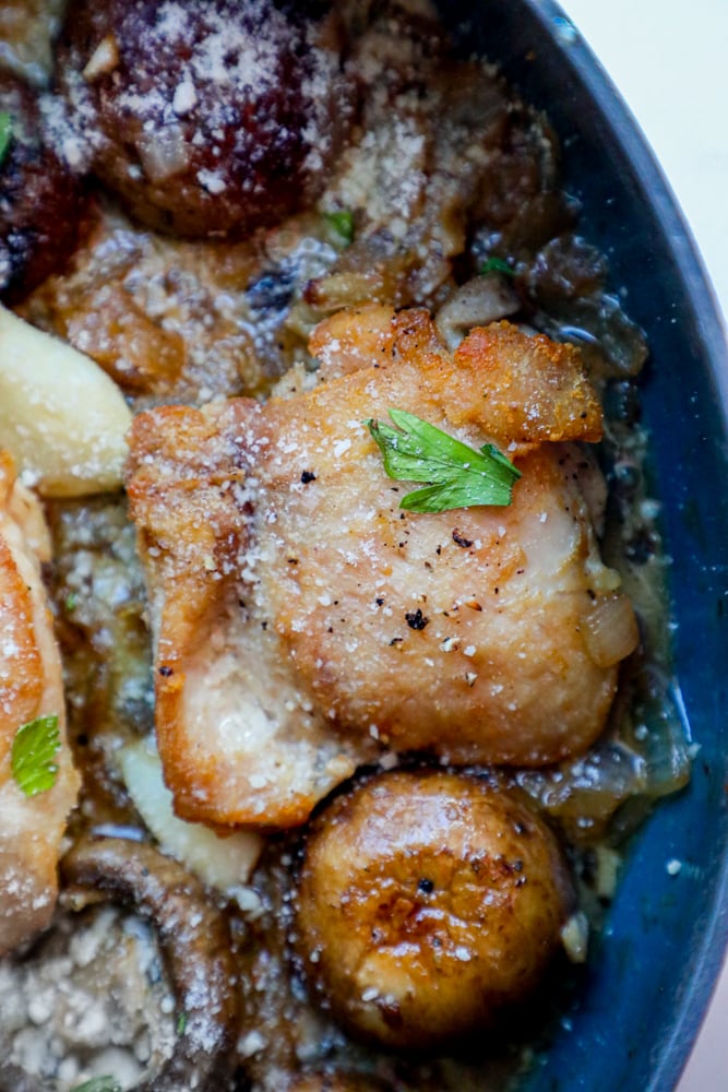 Picture of chicken thighs and mushrooms in a pan. 