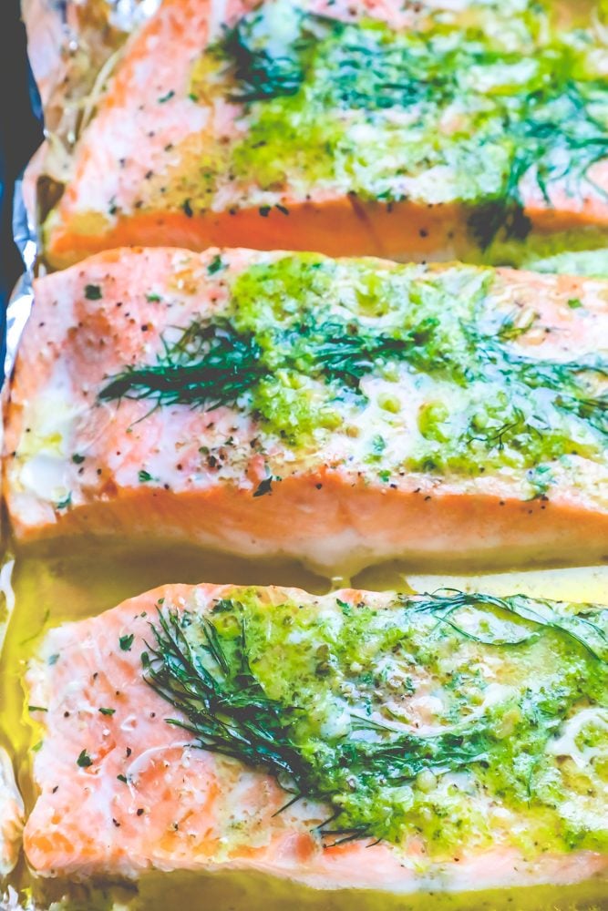 salmon on a tray with butter, pesto, and dill on it