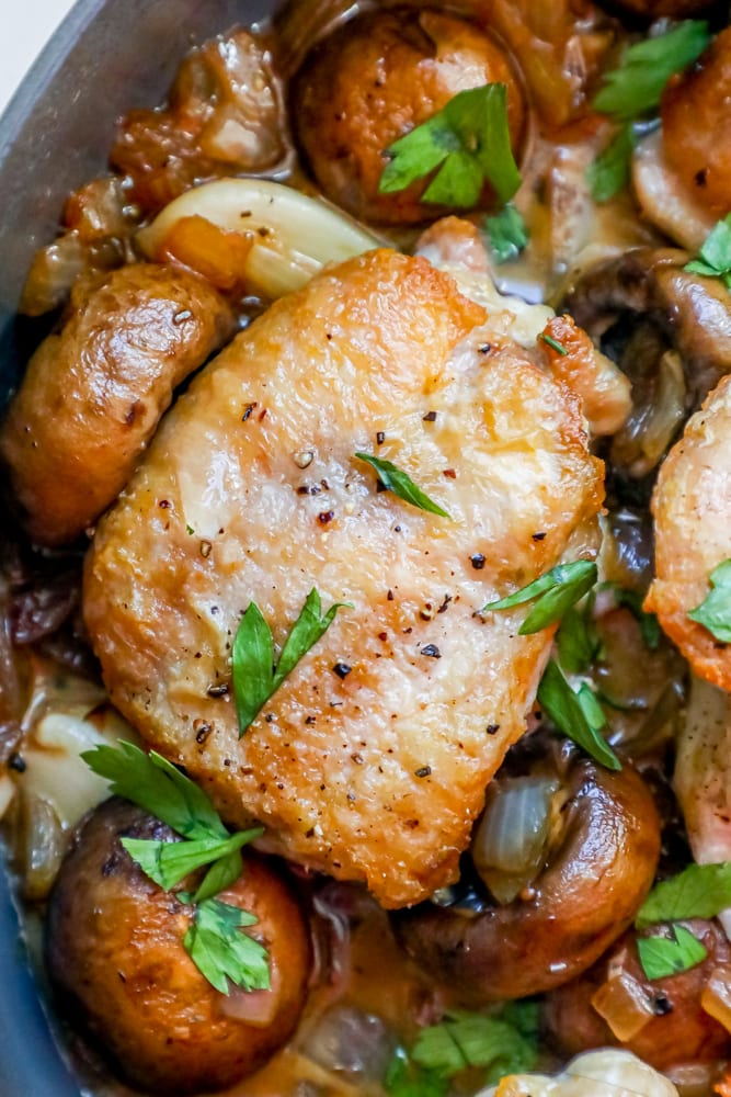 Picture of chicken thighs and mushrooms in a pan. 