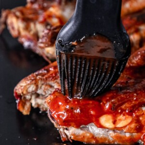 Bbq ribs being dipped in bbq sauce using a slow cooker.