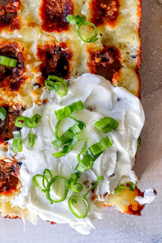 keto chaffle waffles on a countertop with sour cream and green onions