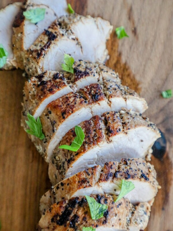 Grilled chicken on a wooden cutting board gently sliced.