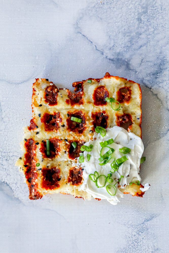 keto chaffle waffles on a countertop with sour cream and green onions