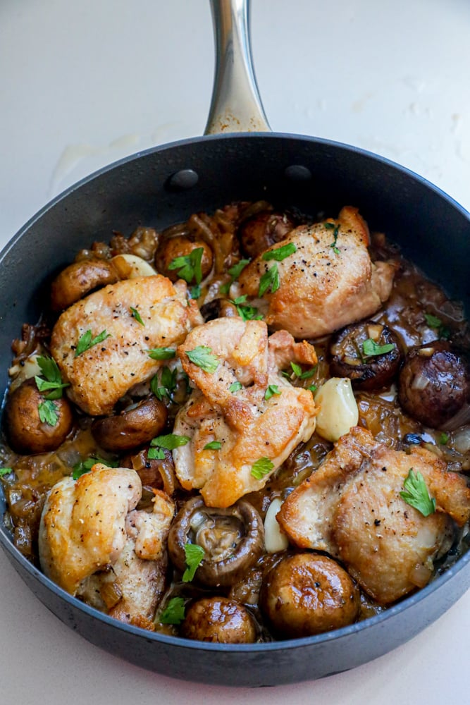 Picture of chicken thighs and mushrooms in a pan. 