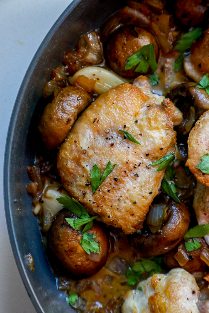 Picture of chicken thighs and mushrooms in a pan. 