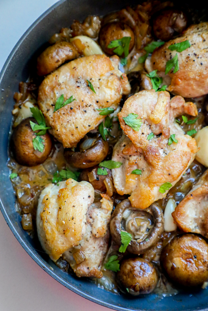 Picture of chicken thighs and mushrooms in a pan. 
