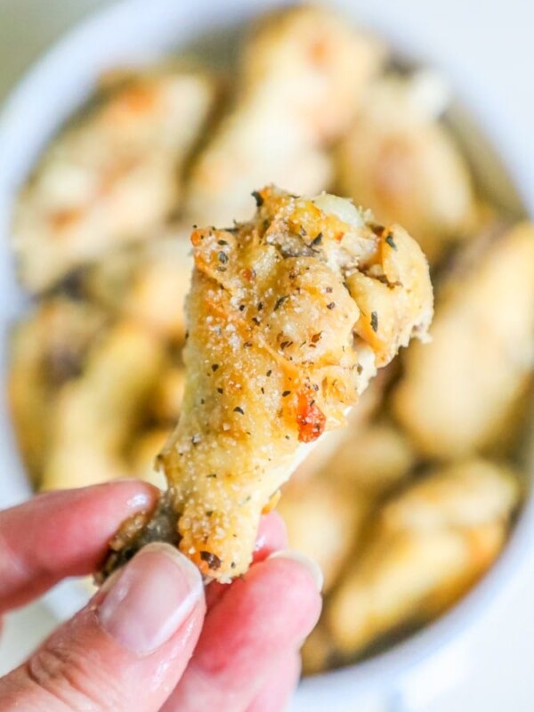 A person holding a small piece of Slow Cooker Garlic Parmesan Chicken Wings.